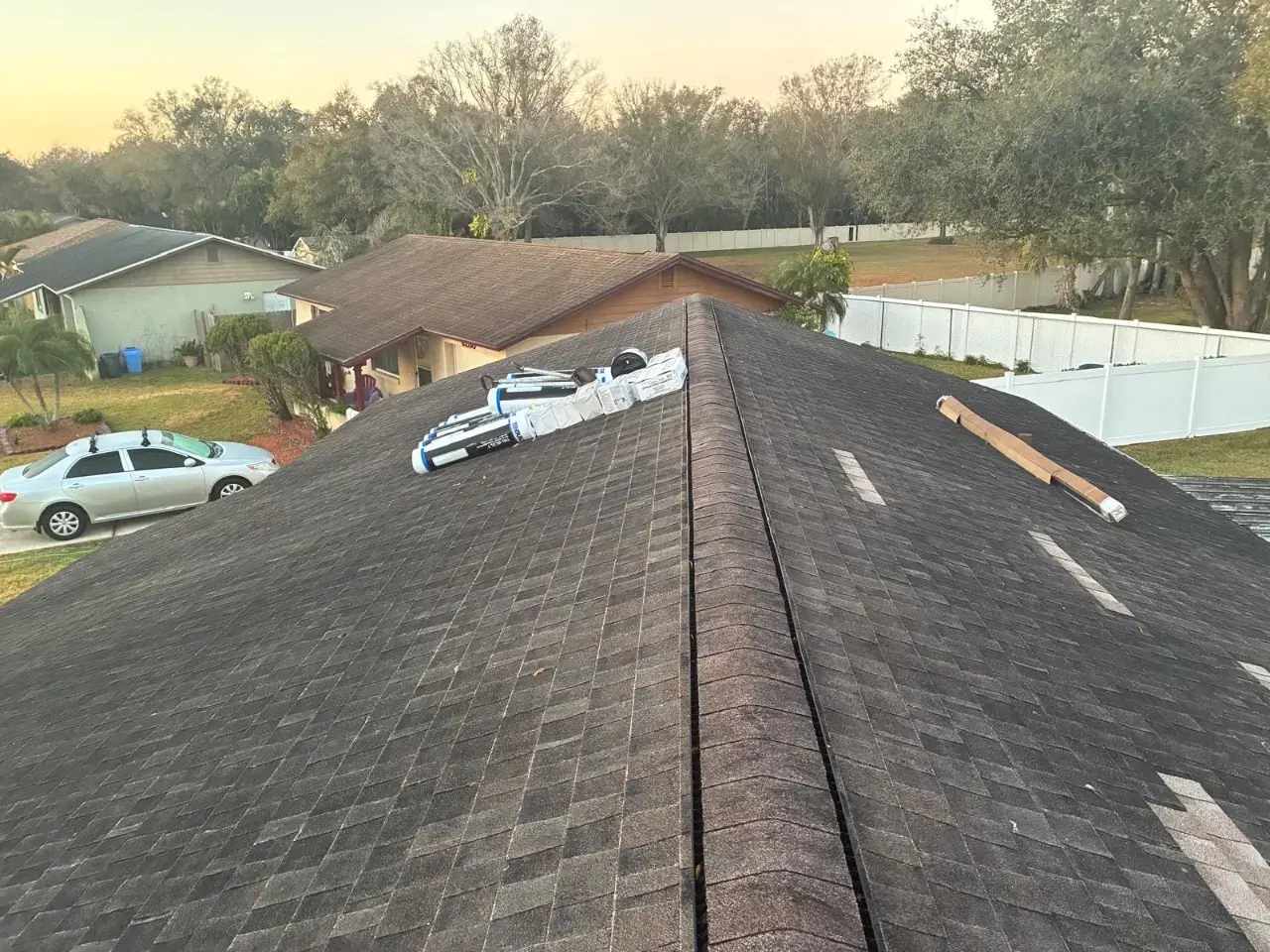 Contact Us Today Roofing materials laid out on a shingled residential roof during a roof repair in a suburban neighborhood